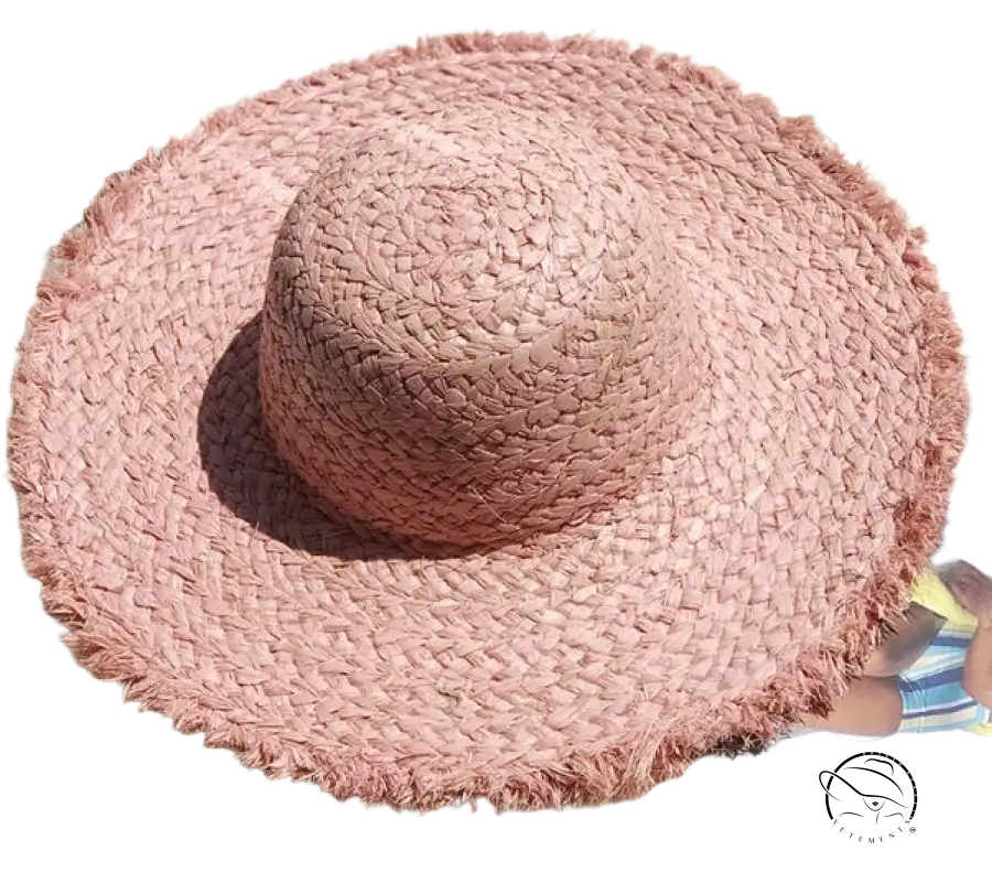 Soft pink woven broad brimmed hat with frayed brim and beige ribbon band