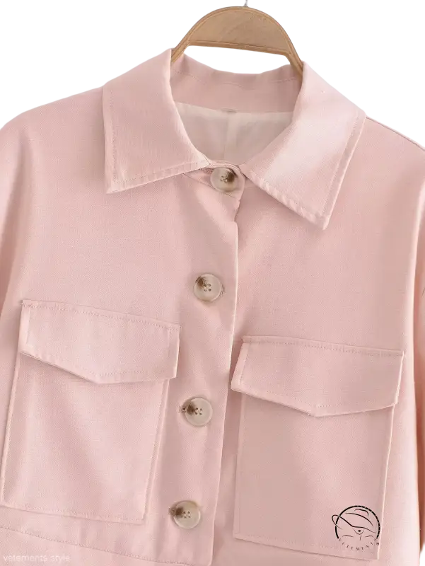 Pale pink button-up shirt with chest pockets hanging on wooden hanger for Pink Pants and Top Blazer High