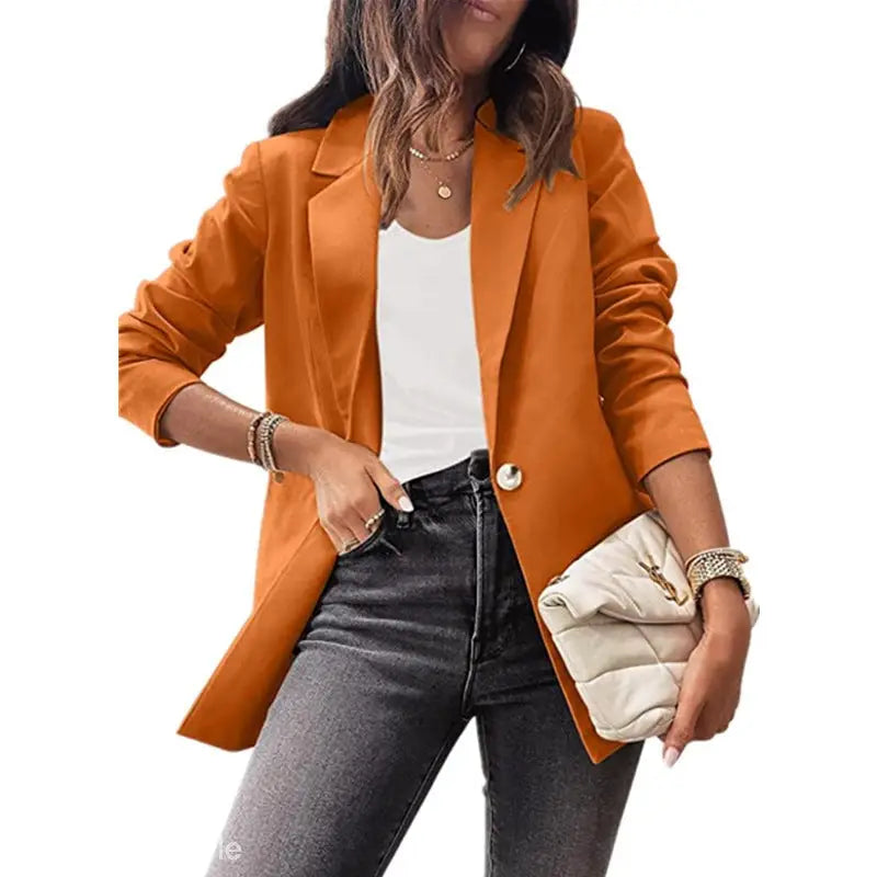Woman wearing a purplish blue slim fit jacket with jeans and a clutch for the office