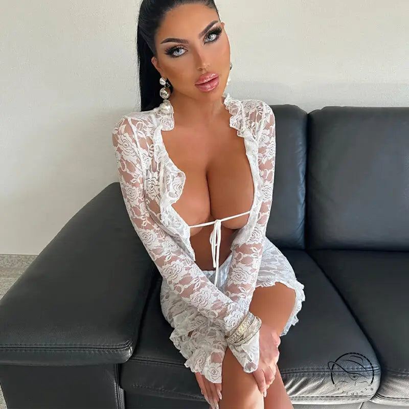Woman in revealing white lace sheath dress with ruffles on leather couch