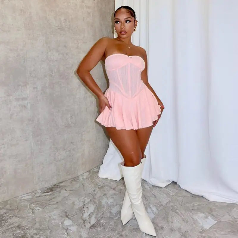 Woman wearing a pink strapless mini dress and white knee-high boots.