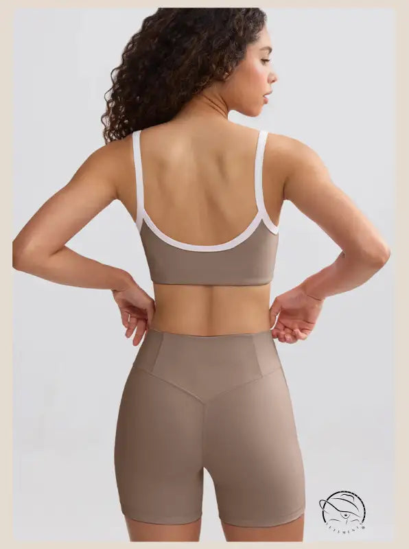 Woman in taupe sports bra and high-waisted shorts for summer yoga clothes, rear view