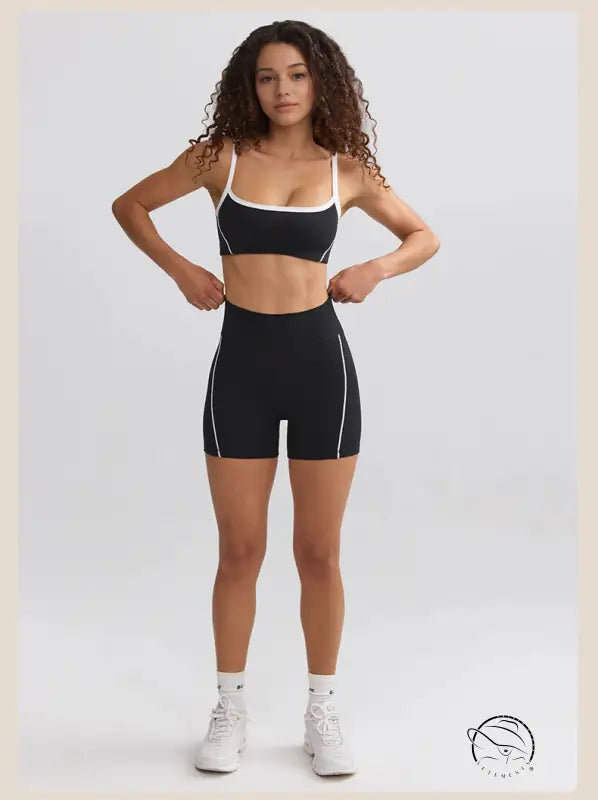 Woman in curly hair wearing black and white athletic attire and white sneakers for summer yoga clothes