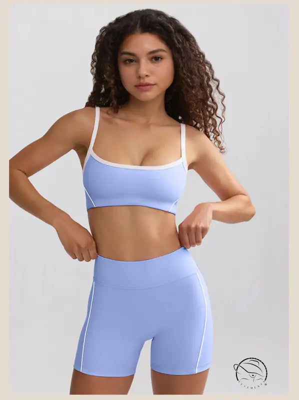 Young woman in curly hair wearing light blue sports bra and high rise summer yoga clothes shorts