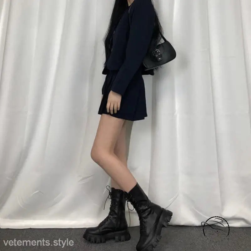 Woman in navy blue dress with stylish lace-up platform boots and black handbag