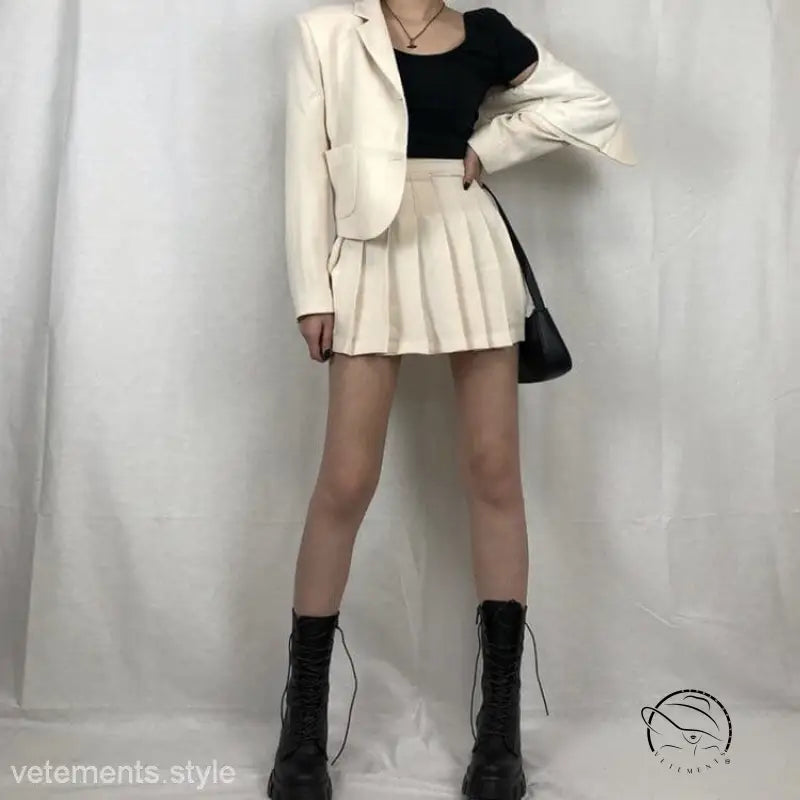 Woman in stylish lace-up platform boots, white blazer, and pleated skirt