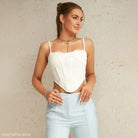 Young woman in white lace crop top and blue high-waisted pants with white boning corset
