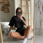 Woman in black lounge set featuring a unique loose summer top and matching two piece suit