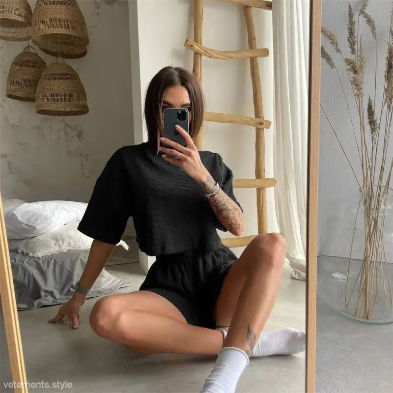Woman in black lounge set featuring a unique loose summer top and matching two piece suit